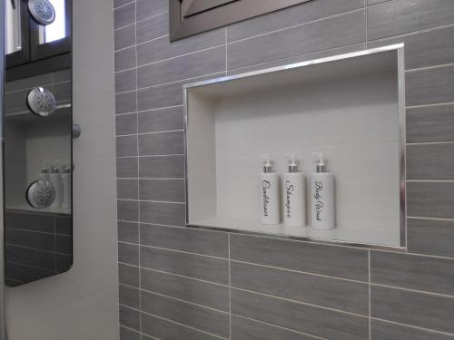 - une salle de bains avec 3 bouteilles de shampoing sur une niche dans le mur dans l'établissement Apartamento El Almencino, à Tolox