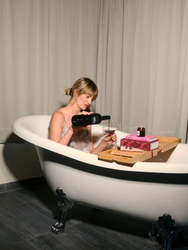 a woman sitting in a bathtub drinking a glass of wine at HUBER's Boutiquehotel in Mayrhofen