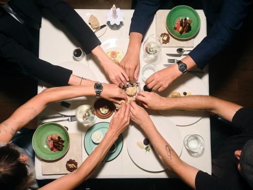 a group of people holding their hands up in a circle around a table at HUBER's Boutiquehotel in Mayrhofen