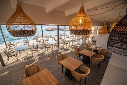 a restaurant with tables and chairs and a view of the ocean at Ramada Loutraki Poseidon Resort in Loutraki