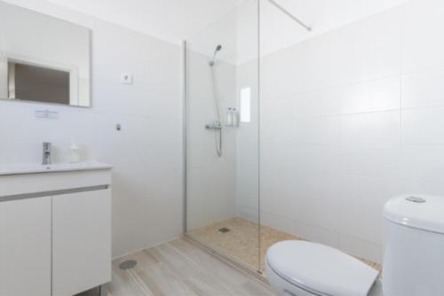 uma casa de banho branca com um WC e uma cabina de duche em vidro. em Galagana Charm House na Golegã