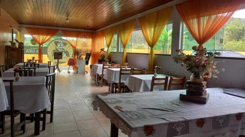 a dining room with tables and chairs and windows at Pousada Vô Lica com piscina in Penha