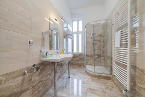 uma casa de banho com um lavatório e um chuveiro em Hotel Aura em Mariánské Lázně
