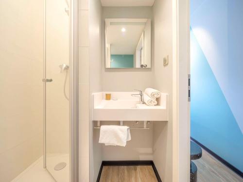 a white bathroom with a sink and a shower at ibis budget Forbach Centre in Forbach