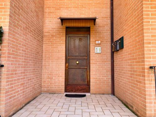 a brown door in a brick building with a brick wall at La casa di Lory in Sarnano
