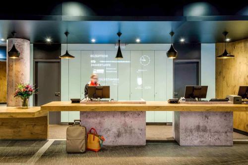 a lobby with a desk with a person in the background at Ibis Hamburg City in Hamburg