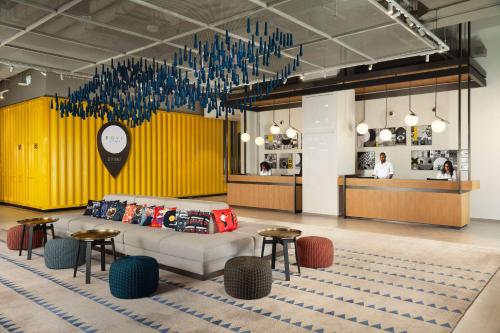 a lobby with a couch and tables and a yellow wall at Rove City Walk in Dubai