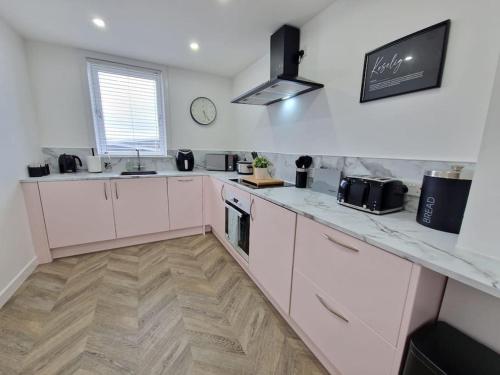 uma cozinha com armários brancos e uma bancada em Koselig Properties em Lerwick