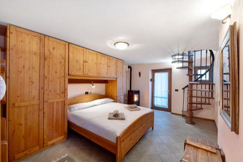 1 dormitorio con 1 cama con armarios de madera y escalera en Baita Margherita, en Casargo