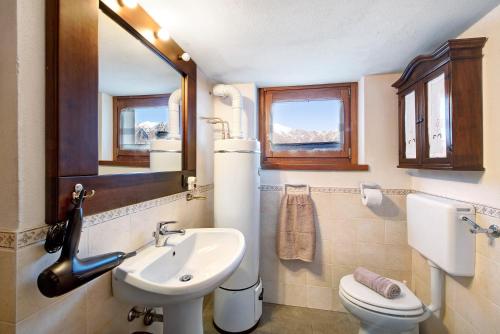 a bathroom with a sink and a toilet and a mirror at Baita Margherita in Casargo