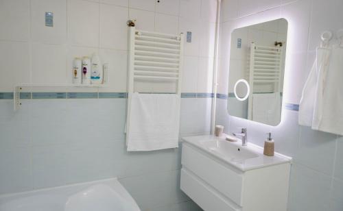 a white bathroom with a sink and a mirror at Exclusive Apartment in Giurgiu