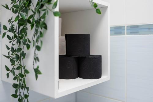 three black towels sitting on a shelf in a bathroom at Exclusive Apartment in Giurgiu