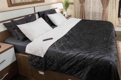 a bed with a black comforter and white pillows at Exclusive Apartment in Giurgiu