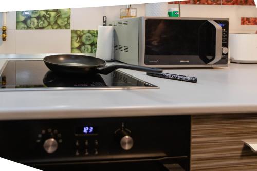 a frying pan on top of a stove with a microwave at Exclusive Apartment in Giurgiu