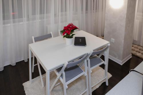 a white table with a laptop and flowers on it at Exclusive Apartment in Giurgiu