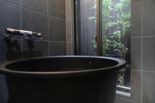 een zwart bad in de badkamer met een douche bij Samurai tei in Kyoto