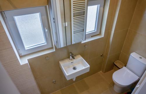 een badkamer met een wastafel, een toilet en een spiegel bij Nest Port View Apartment in Volos