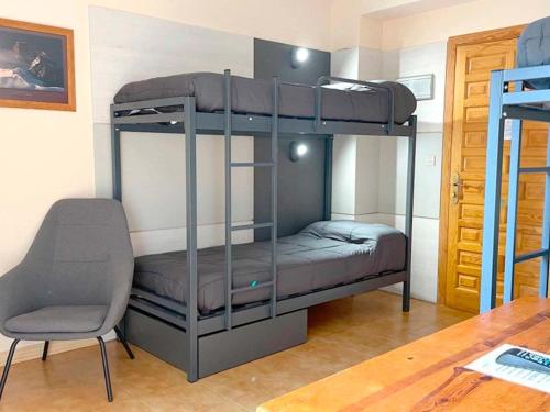 Zimmer mit 2 Etagenbetten und einem Stuhl in der Unterkunft Apartamentos Midi 3000 in Formigal