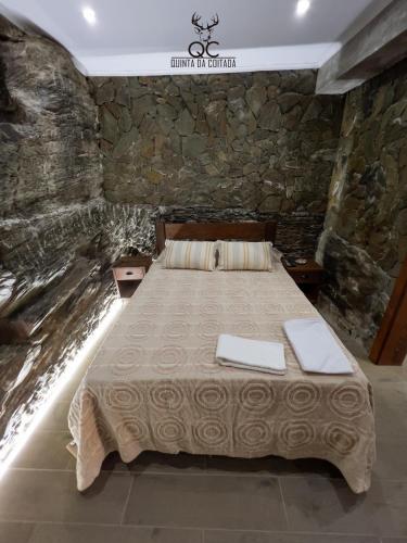 a bed in a room with a stone wall at Quinta da Coitada - Alojamento Local in Soutelo do Douro