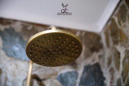 a gold strainer in a bathroom next to a wall at Quinta da Coitada - Alojamento Local in Soutelo do Douro