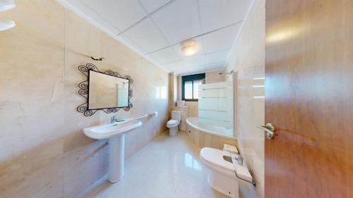 een badkamer met een wastafel, een toilet en een spiegel bij Quiet and Sunny apartment with swimming pool in Ciudad Quesada