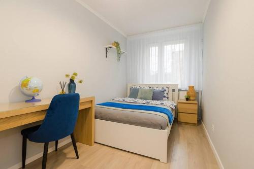a bedroom with a bed and a desk and a blue chair at SuperApart Walerego Sławka 3 in Warsaw