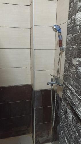 a shower in a bathroom with a stone wall at Sky hostel in Pristina