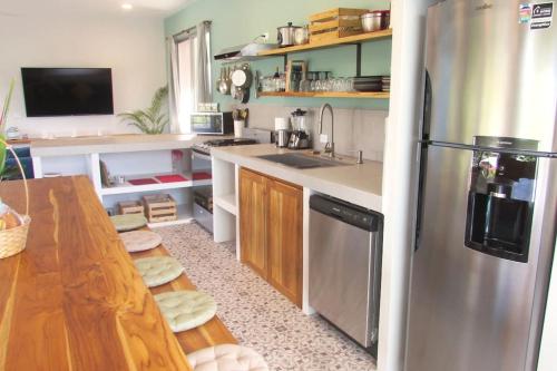a kitchen with a stainless steel refrigerator and a table at Boutique Tropical Retreat, Sleeps 10, Perfect for Friends and Fams in Sámara