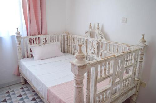 een bed in een kamer met een witte wieg bij Roma Stays - Hibiscus Homes Cozy 3 bedroom near Pride Inn in Mombasa