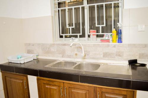 a kitchen counter with a sink and a window at Roma Stays - Hibiscus Homes Cozy 3 bedroom near Pride Inn in Mombasa