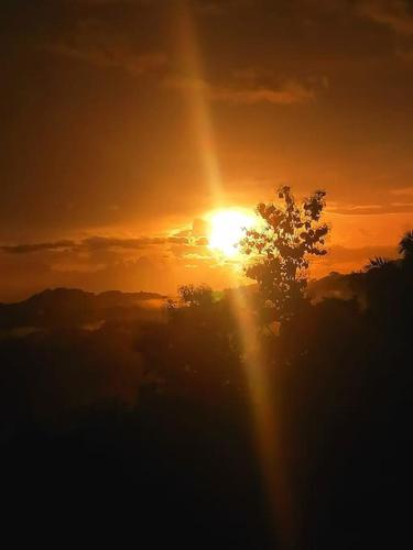 a sunset with the sun setting behind a tree at Boutique Tropical Retreat, Sleeps 10, Perfect for Friends and Fams in Sámara