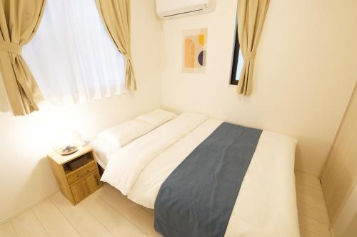 a small bedroom with a bed and a night stand at FINOA Residential Suite Kameari in Tokyo