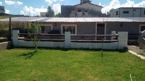 una casa con una valla en un patio en Mecohue en Villa Giardino