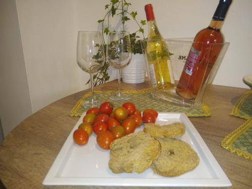 un piatto di biscotti e pomodori su un tavolo con bicchieri da vino di LA FINESTRA SUL MARE a Lendinuso