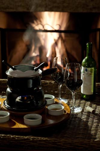 a table with a pot and wine glasses and a fireplace at Pousada Les Roches in Itaipava