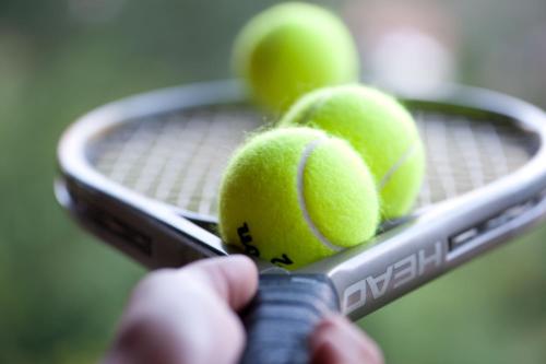 a person holding a tennis racket with four tennis balls on it at Pousada Les Roches in Itaipava