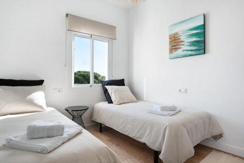 Dos camas en una habitación blanca con ventana. en Ula Home, en Barbate