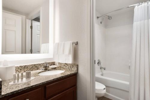 a bathroom with a sink and a toilet and a mirror at TownePlace Suites Boca Raton in Boca Raton