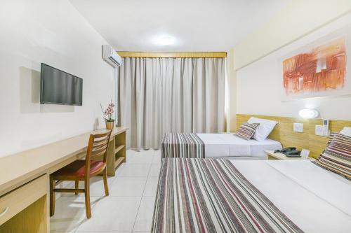 a hotel room with two beds and a desk at Hotel Nacional Inn Piracicaba in Piracicaba