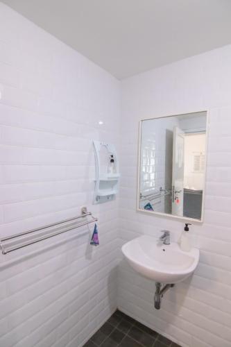 a white bathroom with a sink and a mirror at Harvest Mountain Farm Guesthouse in Bogor