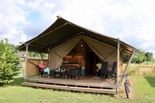 una mujer sentada en una mesa en una yurta en Camping De Heerlijkheid Vorenseinde, en Rucphen