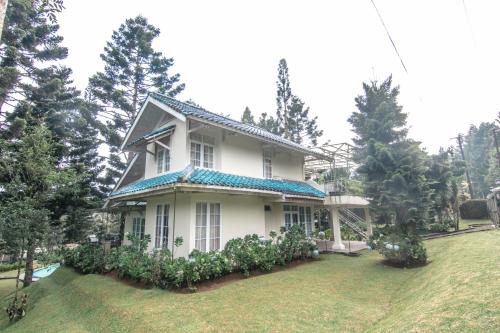 a white house with a blue roof on a yard at Harvest Mountain Farm Guesthouse in Bogor