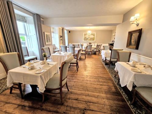 uma sala de jantar com mesas e cadeiras com toalhas de mesa brancas em The Glenbeigh Hotel em Glenbeigh