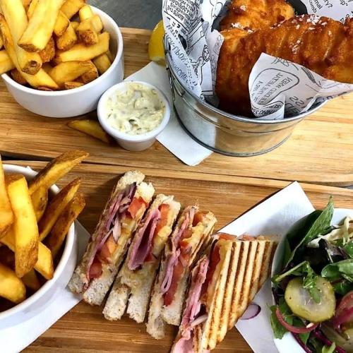 a wooden table with sandwiches and french fries and dip at The Glenbeigh Hotel in Glenbeigh