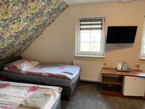 a small room with two beds and a tv at Pokoje gościnne Rubin in Zielona Góra