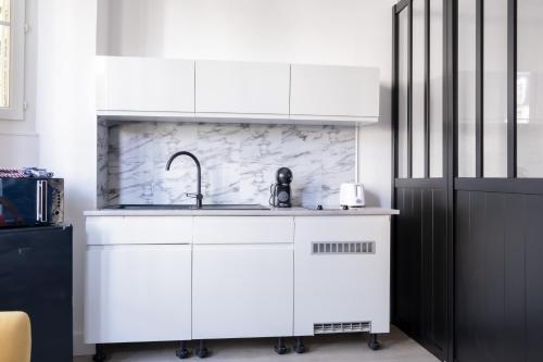 una cocina con armarios blancos y fregadero en Résidence Peace en Le Bourget