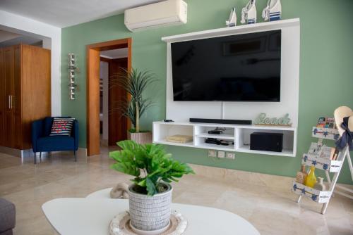 un soggiorno con TV a schermo piatto su una parete verde di Riviera Azul Playa Dorada a San Felipe de Puerto Plata