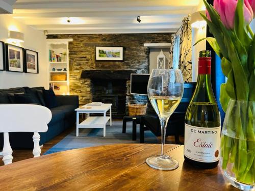 a bottle of wine and a glass on a table at Gill Cottage, The Gill. in Ulverston