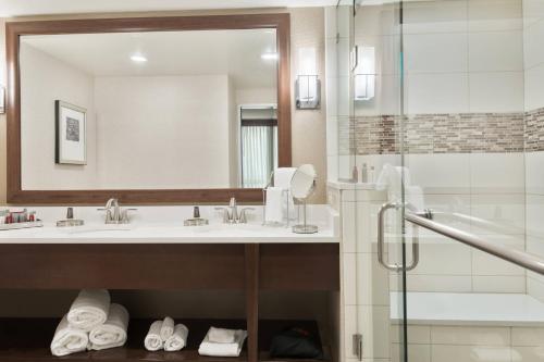 baño con 2 lavabos y ducha de cristal en Columbus Airport Marriott, en Columbus