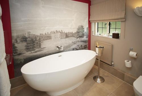 a bath tub in a bathroom with a painting on the wall at Pink Cottage in Shifnal